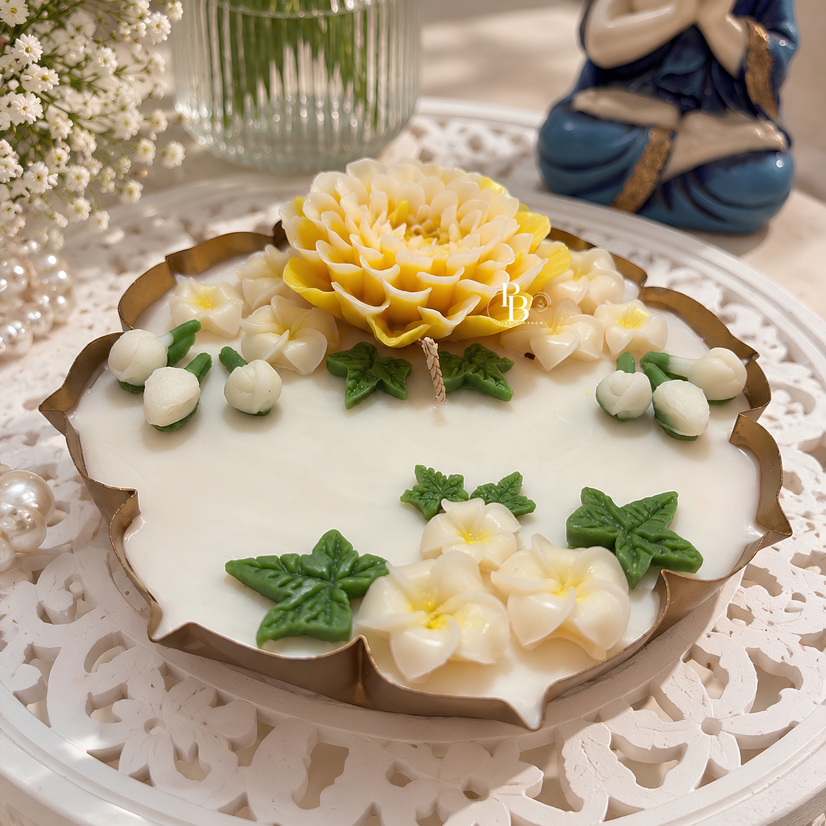 Floral wax candle with yellow center bloom, white petals, green leaves on a base