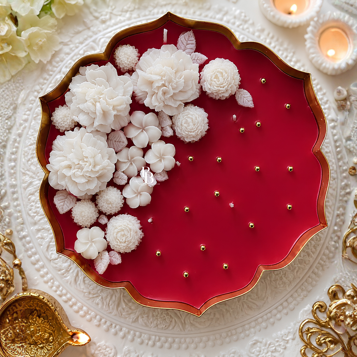 White floral candle in gold-trimmed tray with white blossoms on red wax