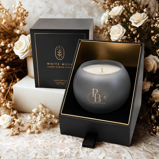 Luxury scented candle in matte dark gray jar with gold logo, shown with gift boxes open