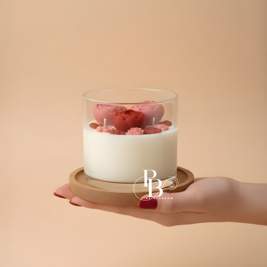 Peony flower candle in clear glass jar with pink blossoms over white wax on wooden base