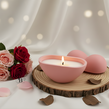 Pink heart-shaped candle in a bowl with lid off to the side, on wood slice.