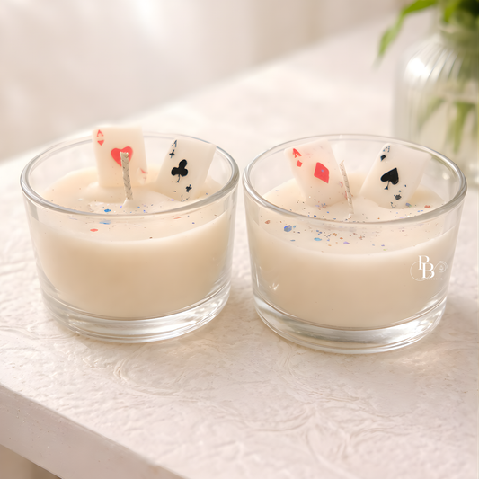 Scented candle in clear glass jar with playing-card wax toppers, two candles