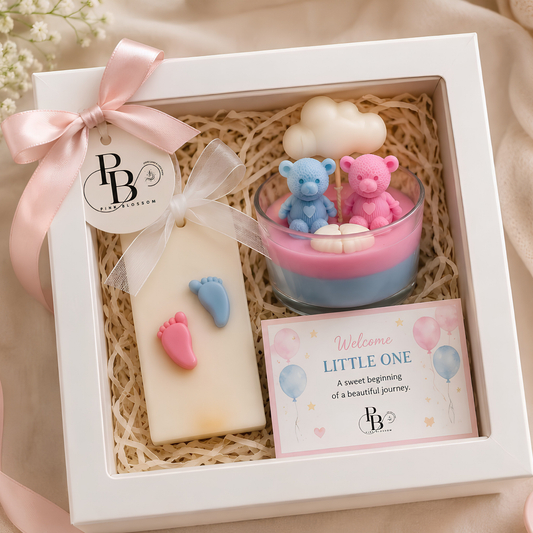 Baby shower gift hamper in white box with pink ribbon, candle and heart-shaped keepsakes