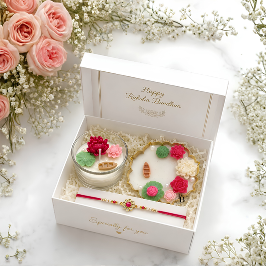 Luxury Raksha Bandhan gift hamper in open white box with pink floral candle and rakhi bracelet