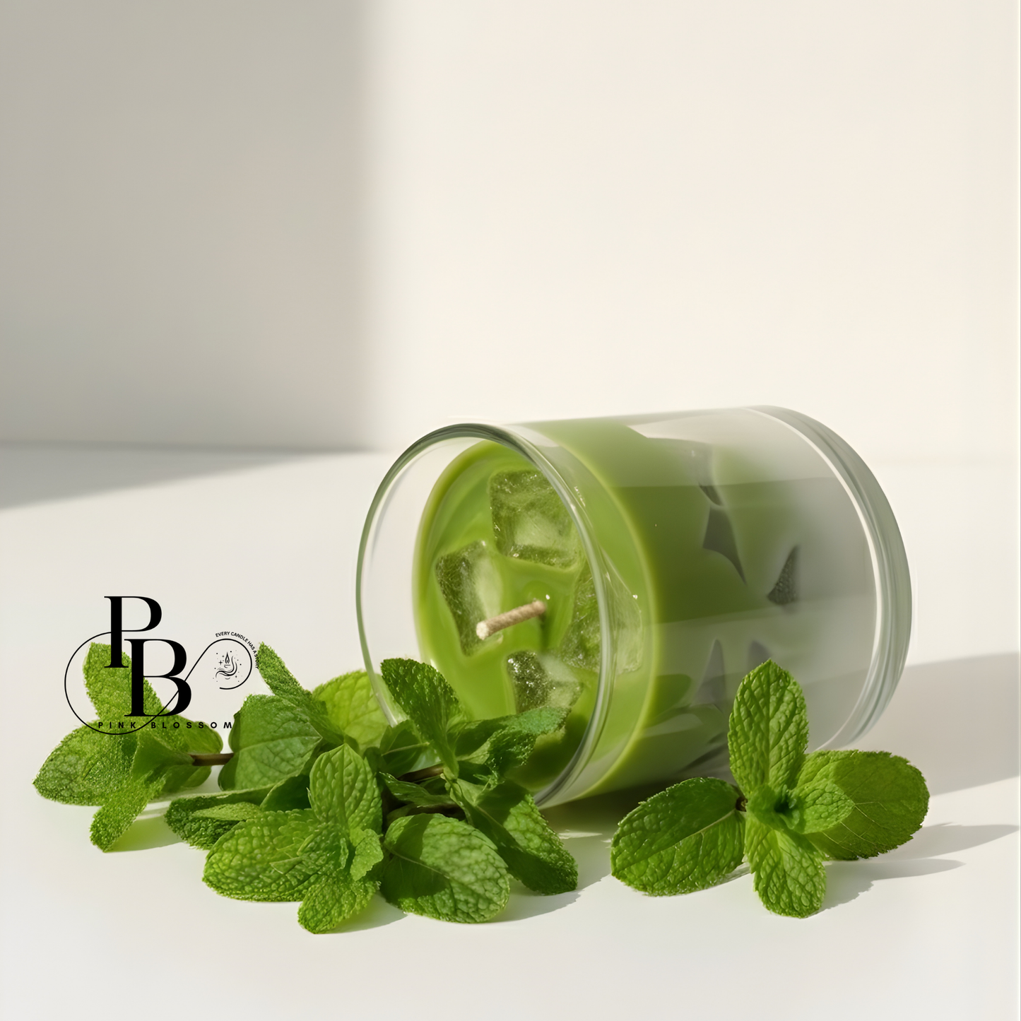 Mint-scent candle in clear glass, green wax with mint leaves and tilted jar