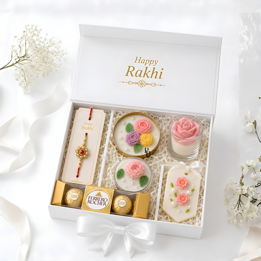 White Raksha Bandhan gift box with rakhi, pink floral candles, and Ferrero Rocher chocolates