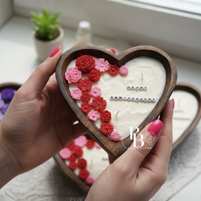 Heart-shaped floral candle in hand, “Happy Anniversary” with pink and red roses