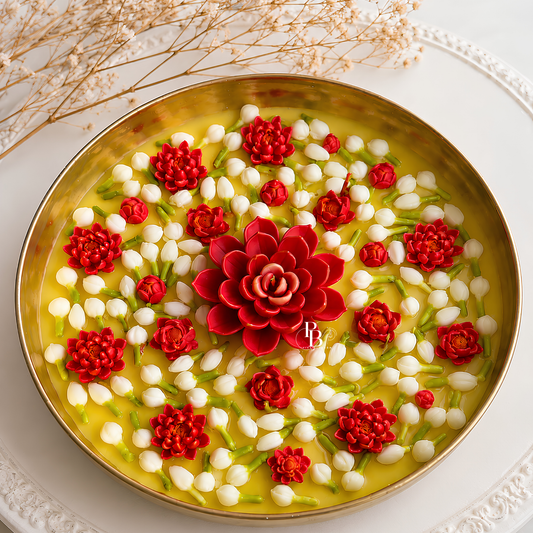 Round decorative candle with red flower centerpiece and floating jasmine buds