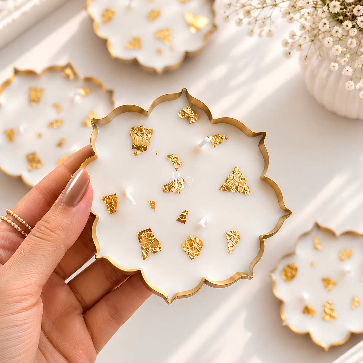 Hand holding gold leaf luxe candle lid: white scalloped wax top with gold flecks