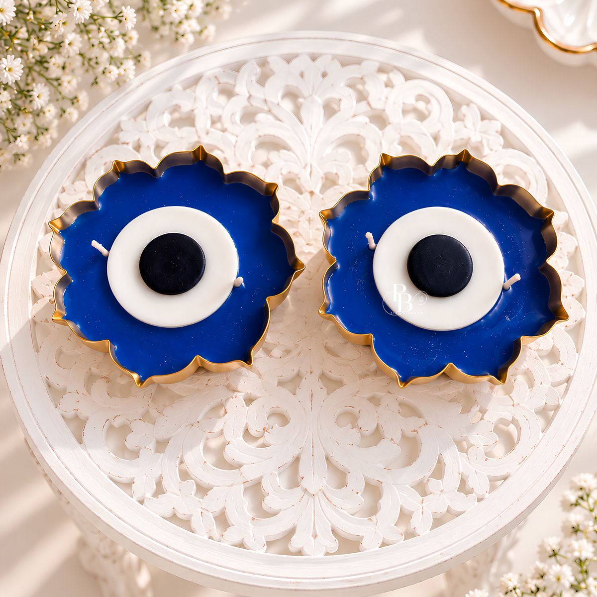 Duo blue flower-shaped candles with gold edges and white center, in clear tray