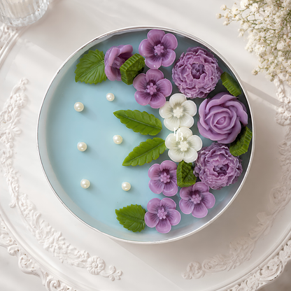 Scented candle in round blue wax with purple flowers, green leaves, and pearl-like dots