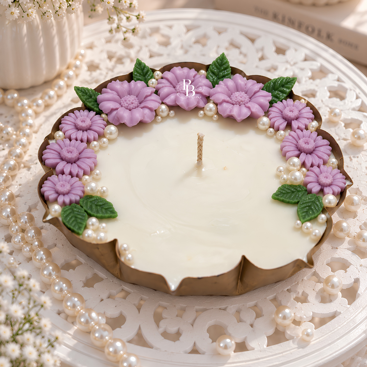 Decorative lilac pearl candle with purple blossoms, pearl beads, and a visible wick.