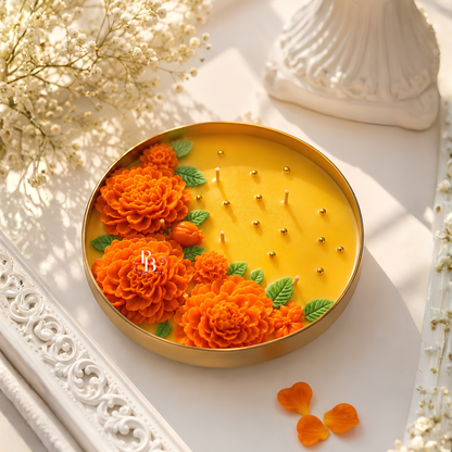 Round urli candle with golden rim; orange marigolds on yellow wax with wick tips.